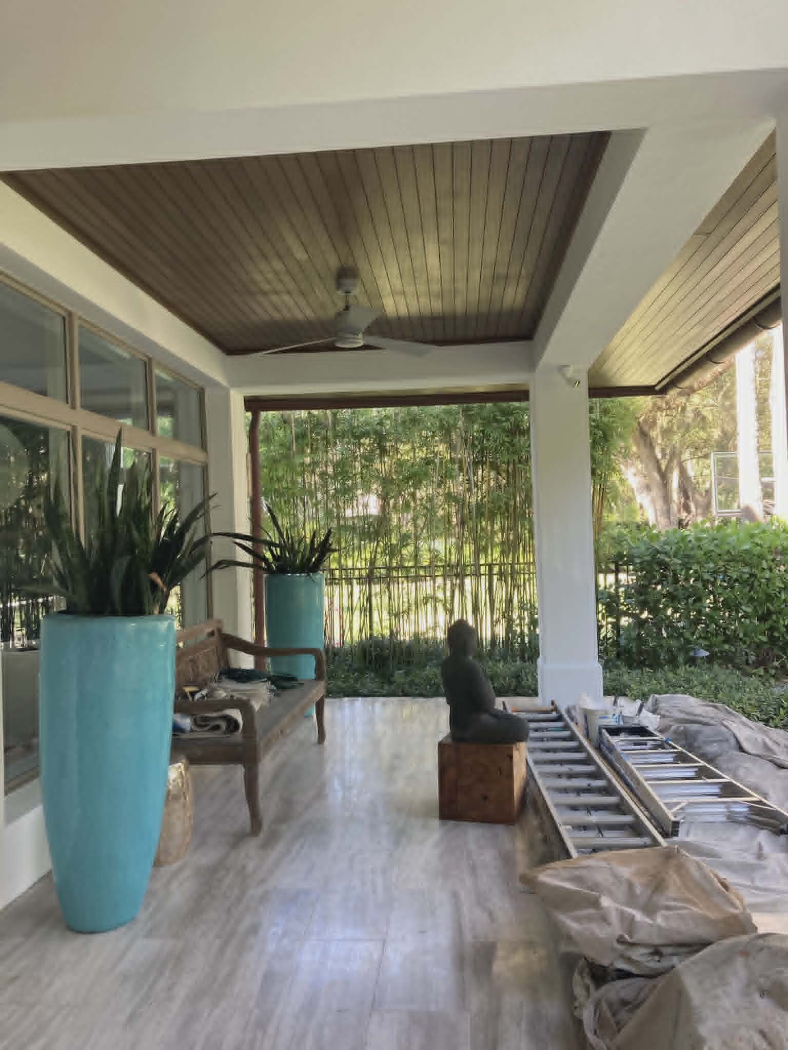 Covered outdoor lanai with a stained tongue-and-groove wood ceiling and crisp white columns by Randy's Painting & Drywall
